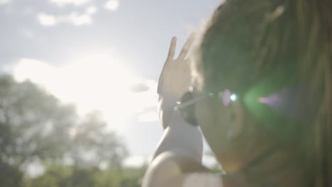 close up back view of a woman looking at the son and hiding herself from the son with her hand. young woman with dreads playing