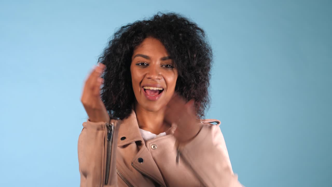 Young African American black woman waving hand hello. Greeting, say Hi to camera. Beautiful young mixed race trendy girl with afro hairstyle. 4k