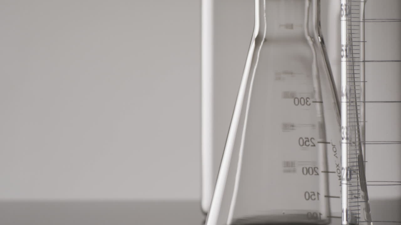 Video of close up of glass laboratory beakers and dishes with copy space on white background