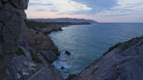 Time-lapse-captures-rocky-sea-coastline-during-beautiful-sun-rise-over-mountain-range