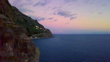 Glorioso-Paisaje-De-Puesta-De-Sol-Del-Océano-Tranquilo-Que-Rodea-La-Montaña-Rocosa-En-La-Costa-De-Madalena-Do-Mar,-Isla-De-Madeira,-Portugal---Toma-Panorámica-Aérea