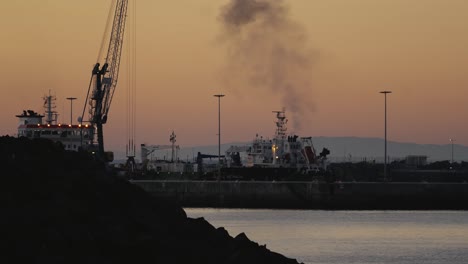 industrial ships in sines port or harbor of portugal, evening view, orange sky