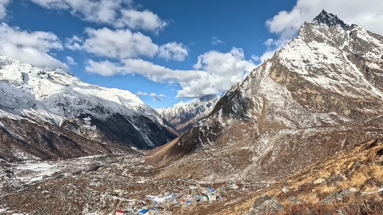 con vistas al vasto valle desde kyanjin ri, con el pintoresco pueblo de kyanjin gompa ubicado debajo de las cumbres nevadas de langtang lirung, resaltado por parches de hierba árida