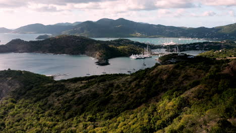 Toma-Aérea-De-La-Puesta-De-Sol-En-Puerto-Inglés-En-Antigua,-Caribe-Con-Vistas-De-Yates,-Veleros,-Puerto-Deportivo,-Bahía-Y-Acantilados