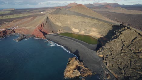 drone flight over a bay in the ocean with black sand beach