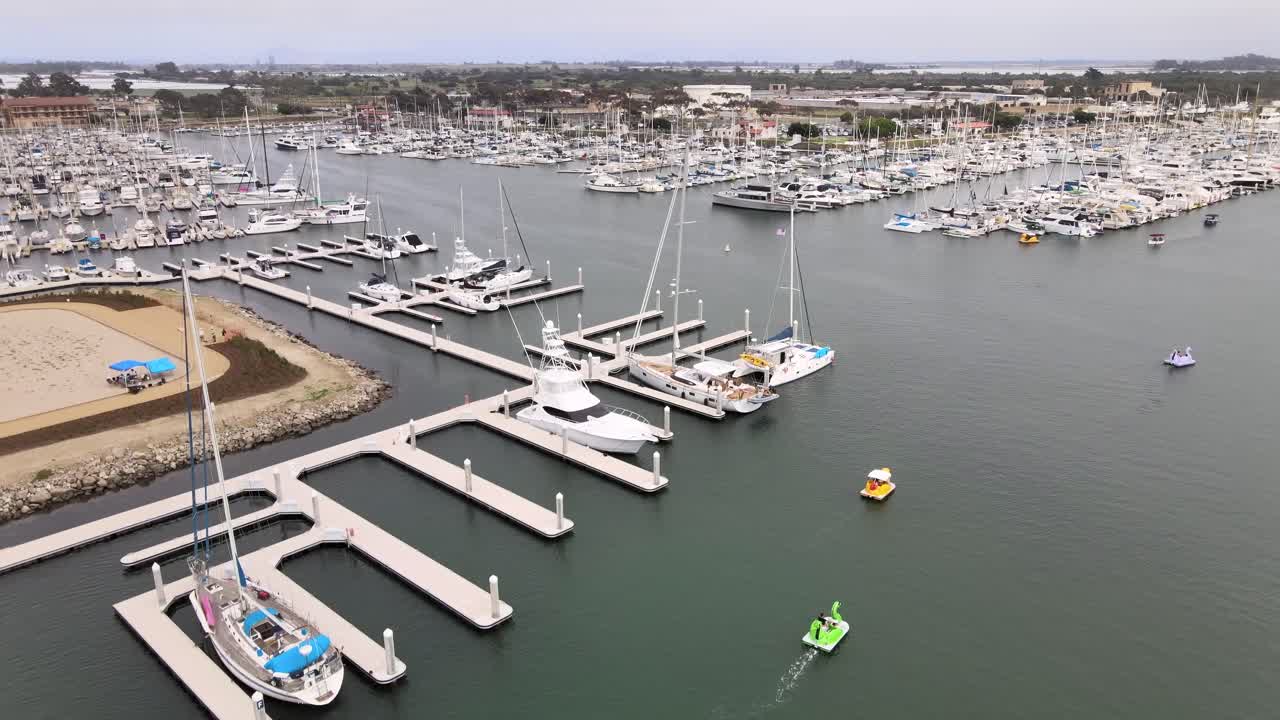 Ascenso aéreo, puerto de Ventura sobre embarcaciones en aguas tranquilas en un día nublado.