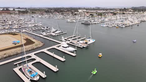 aerial rising, ventura harbor over boats calm water on cloudy day