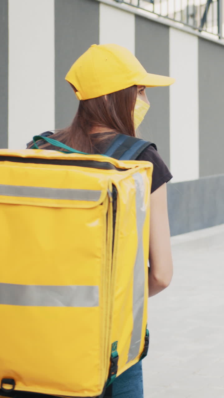 Delivery person with a yellow thermal bag walking on the street