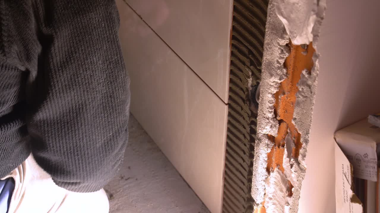 Worker tiling wall with adhesive in bathroom renovation project