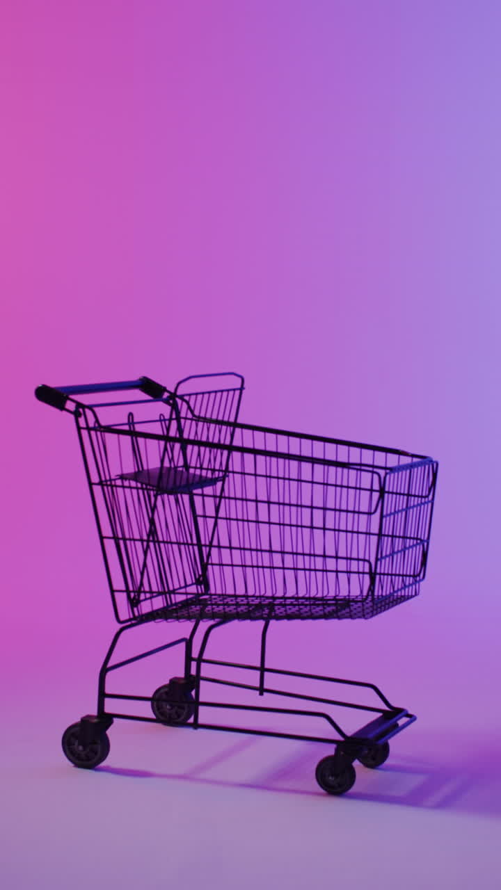 Vertical video of shopping trolley with copy space over pink neon background