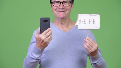 senior handsome man holding phone and selfie paper sign