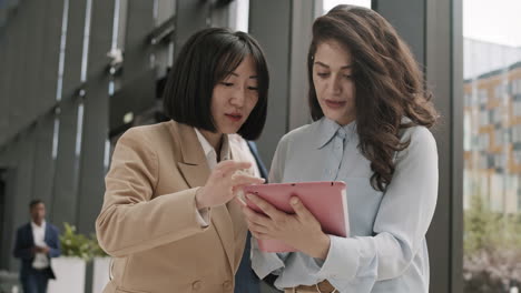 dos mujeres de negocios diversas usando tableta en la oficina