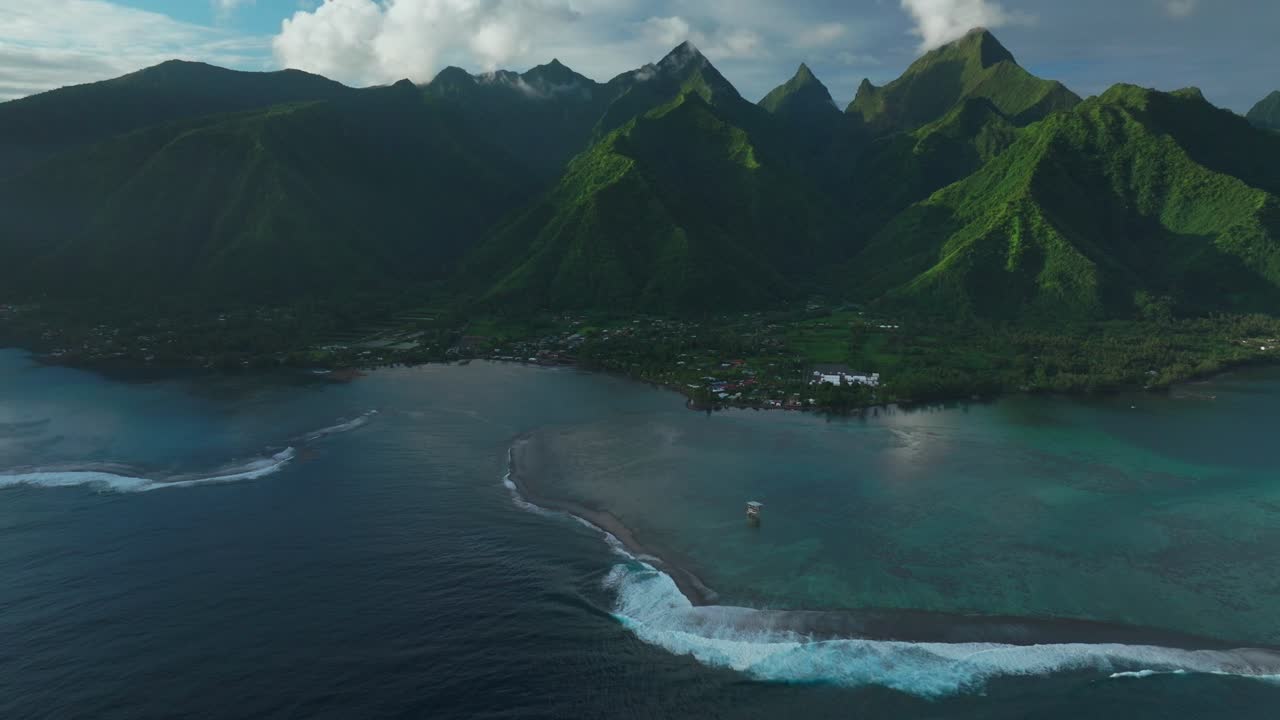 Summer 2024 Paris OlympicsTeahupoo Tahiti aerial drone view French Polynesia venue surf judge tower French Polynesia Pacific Ocean coral reef break channel mountains afternoon forward pan up opening