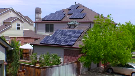 zoom out from solar panels adorning the tops of a house in a residential neighborhood