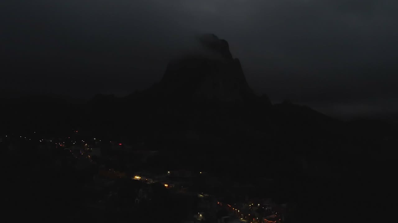 Cidade de Bernal no México, vista aérea noturna, destaques das montanhas, levemente iluminada