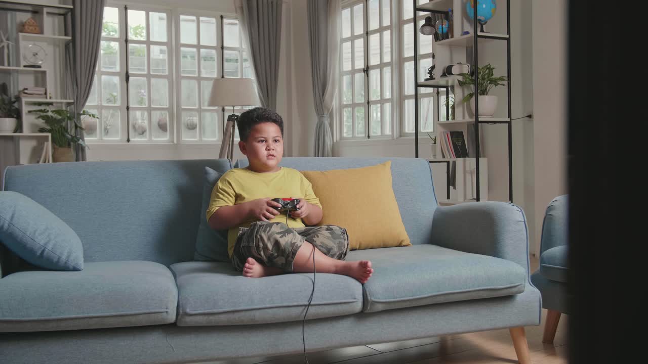 Young Boy Seating On A Couch, While Playing Exited Computer Game