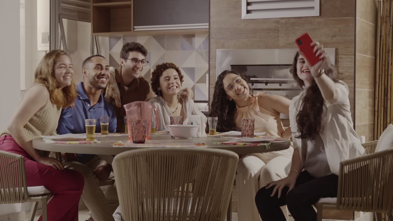 Friends enjoying a social gathering, taking selfies and laughing together