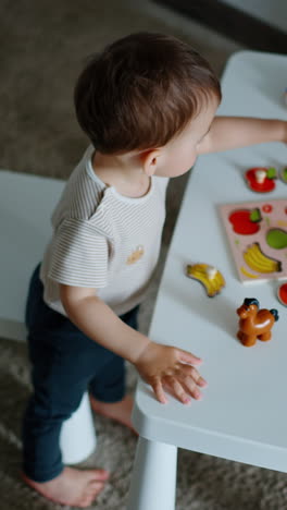 toddler baby learning fruit. caucasian child plays on the little table. view from top. vertical video