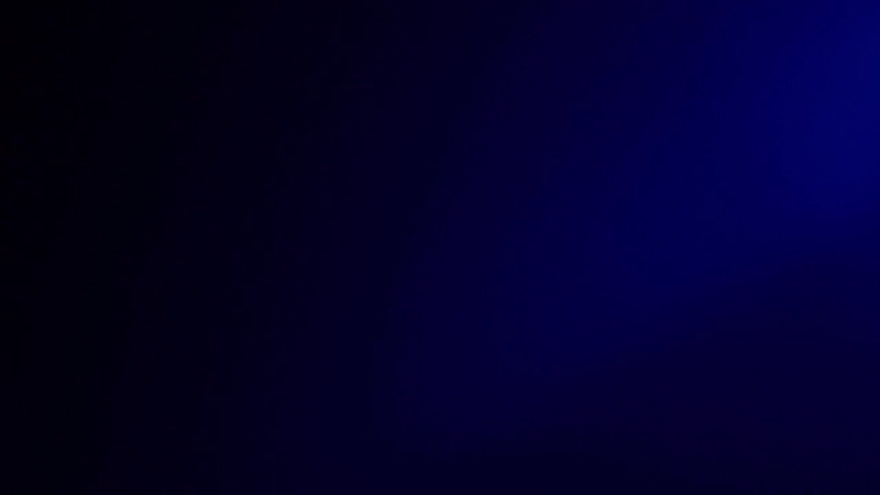 Abstract shot of a foggy blue light effect moving across a black background, creating a soft glowing visual