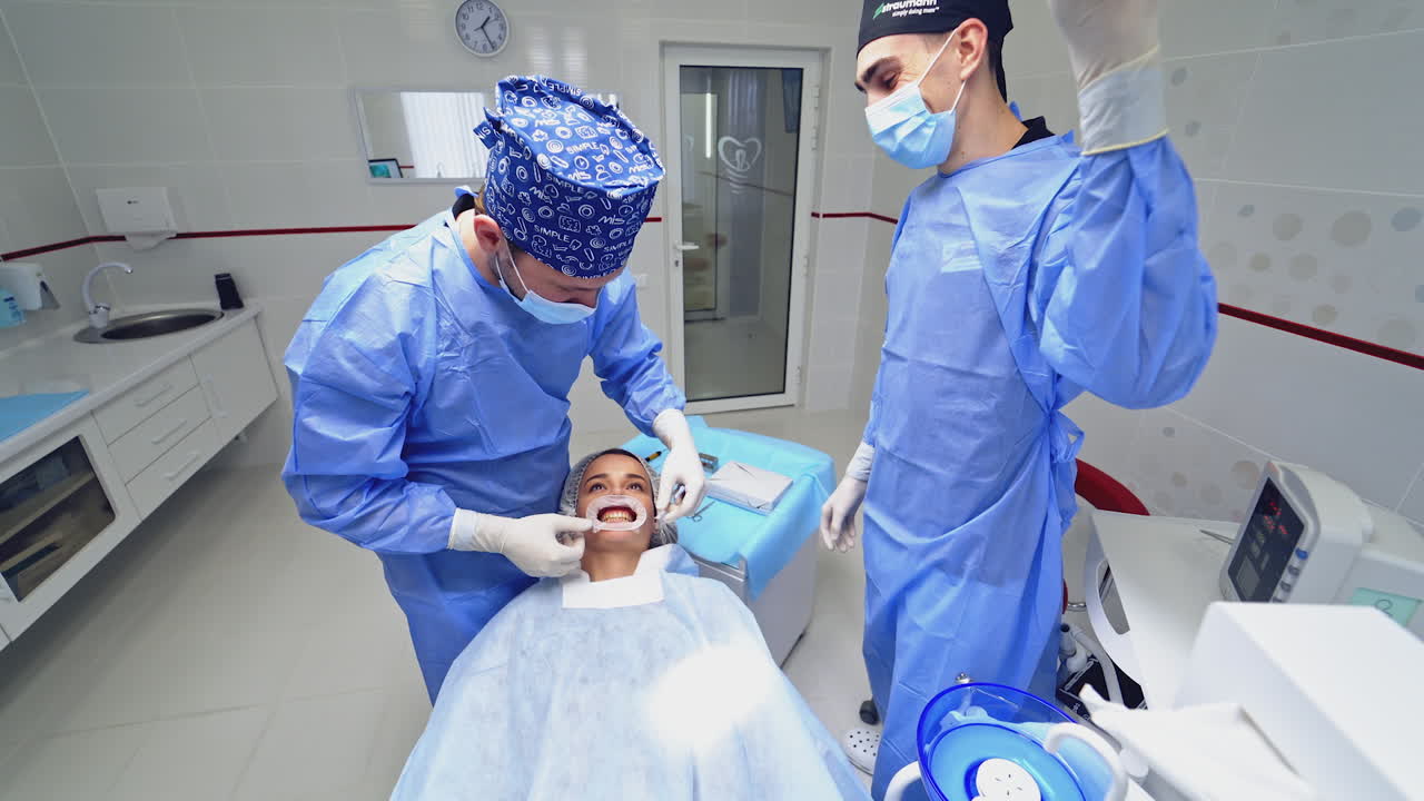 Dentist preparing female patient for dental treatment. Treatment of teeth in a modern clinic. Restoration of a healthy smile.