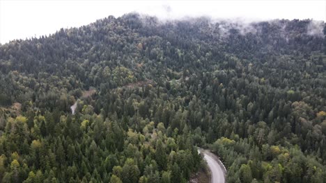 Toma-Aérea-De-Niebla-Pasando-Por-Montañas-Verdes.-Coches-De-Carretera.