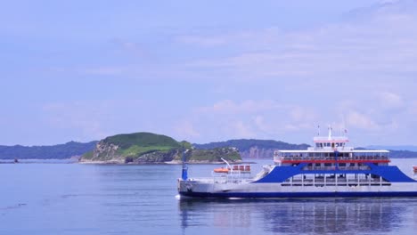 ferry crossing the screen with mountains on the horizon in costa rican landscape on sunny day with cloudy sky