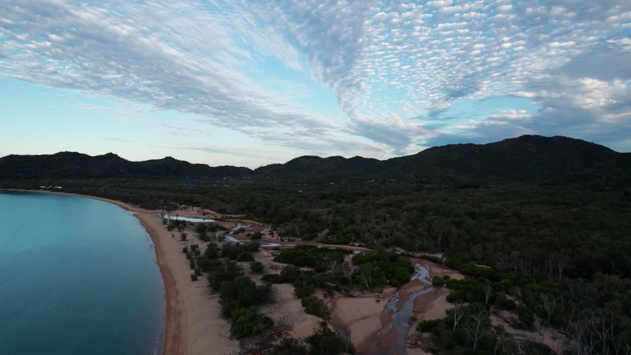 drone ascendente disparado sobre la playa de horseshoe bay en la isla magnética al atardecer con nubes en el cielo, queensland, australia