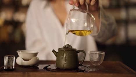 woman pouring tea from a teapot into a cup