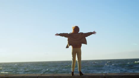 Woman-standing-with-arms-outstretched-in-the-beach-4k