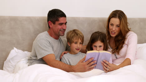 Padres-Felices-Y-Niños-Leyendo-Juntos-En-La-Cama