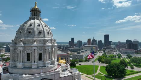 Bandera-Americana-Ondeando-En-El-Edificio-Del-Capitolio-De-Minnesota-Con-Vistas-Al-Horizonte-De-Saint-Paul,-Mn