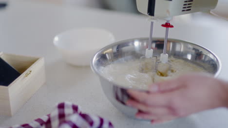 woman using mixer and mixing pancake batter in bowl