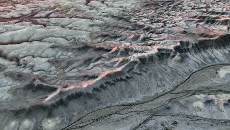 Scenic grey mountain panorama illuminated by orange sunset light, aerial forward