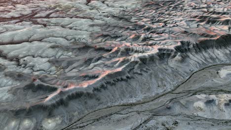 scenic grey mountain panorama illuminated by orange sunset light, aerial forward