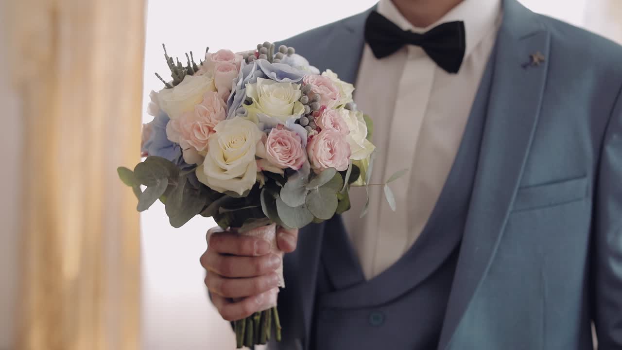 el hermoso novio con un hermoso ramo de bodas. fondo claro