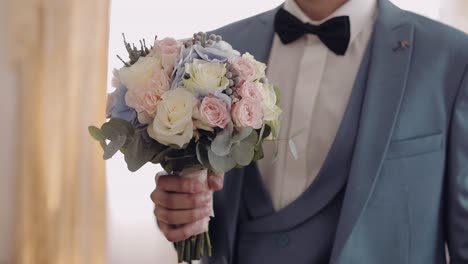 Handsome-groom-with-beautiful-wedding-bouquet.-Light-background