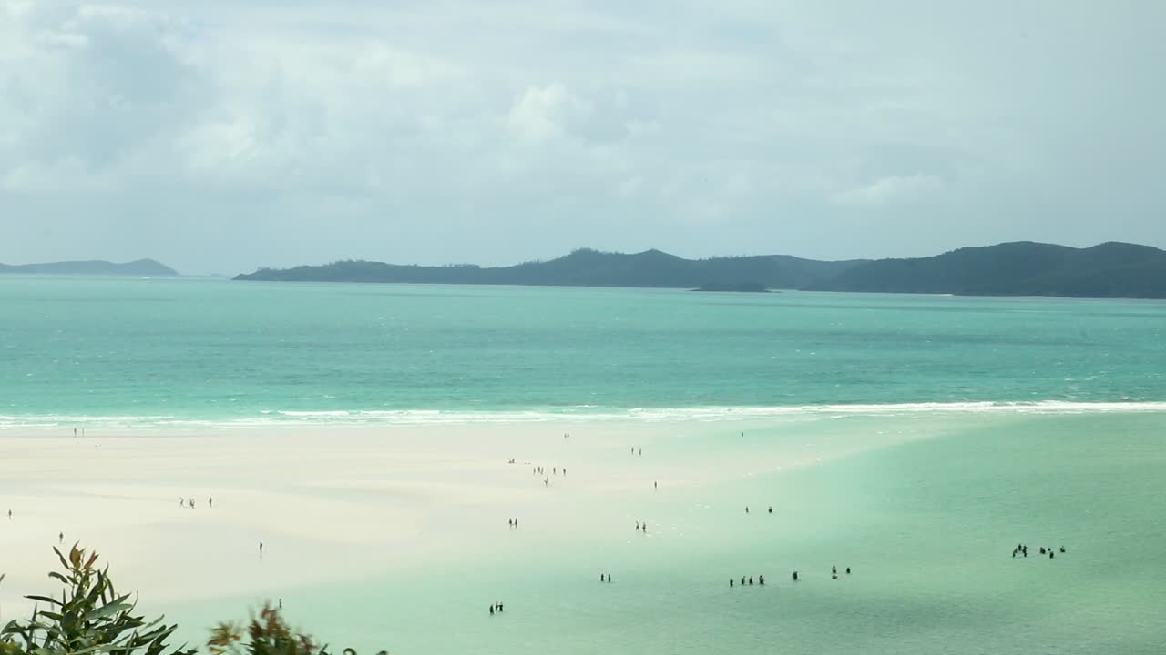 Whitehaven beach from a lookout with tourists like little black dots on the white sand.