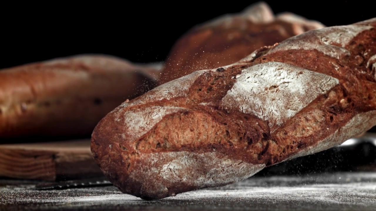 Freshly Baked Baguette Falling onto Flour-Dusted Surface in Slow Motion