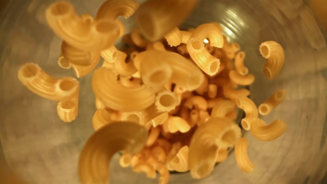 Maccheroni secchi che cadono al rallentatore in un barattolo di vetro