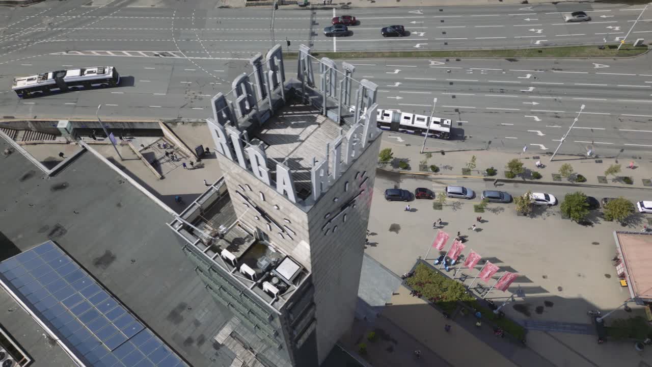toma aérea cinematográfica del dron de la torre del reloj de riga y luego avanzando hacia una carretera principal en la calle el 13 de enero, letonia, europa, drone parte 1