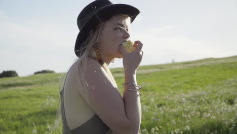 slomo of young woman eating an apple in a field of flowers