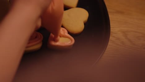 heart-shaped cookies being decorated with pink icing