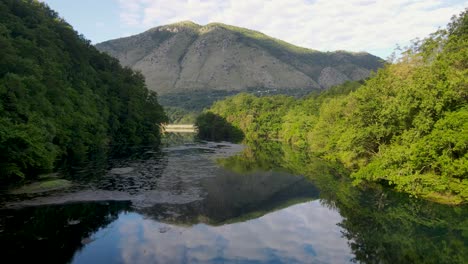 Picturesque-scenery-of-Blue-Eye-water-spring,-a-popular-tourist-attraction-in-Albania,-with-the-clouds-reflected-on-the-water,-creating-a-mesmerizing-and-tranquil-view