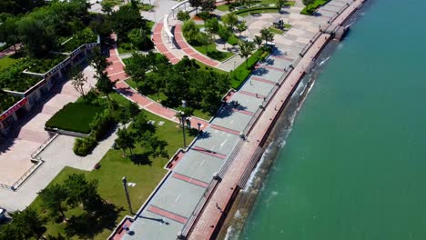 Aerial-view-of-Weihai-Happiness-Park-located-in-the-downtown-area,-drone-approaching-the-main-boulevard-seaside-with-Yellow-Sea-in-Shandong-province-China