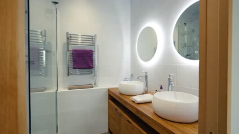 baño de diseño moderno para 2 personas, luces led detrás de los espejos con lavabo de madera