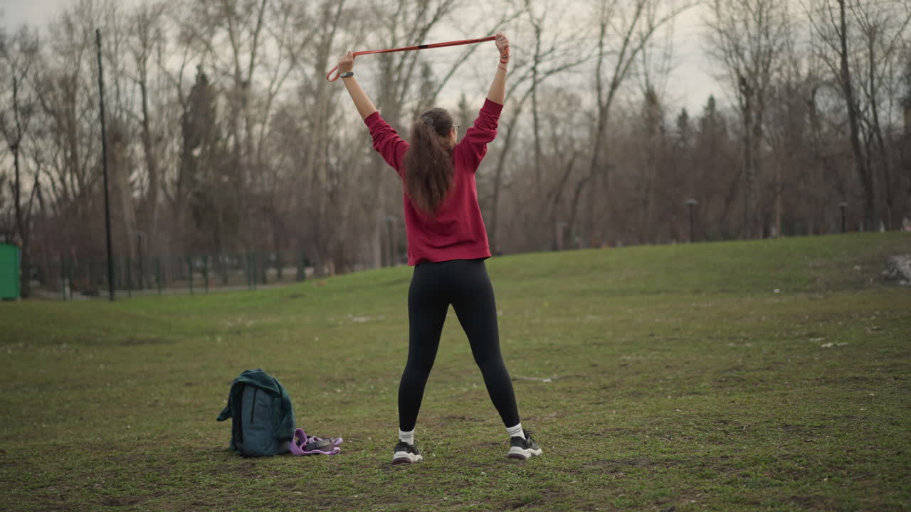 Energetic Caucasian Woman Doing Ribbon Workout, Lively White Woman Engaging In Grassside Ribbon Cardio Session, Energetic Caucasian Female Performing Rhythmic Ribbon Exercises In Park Setting