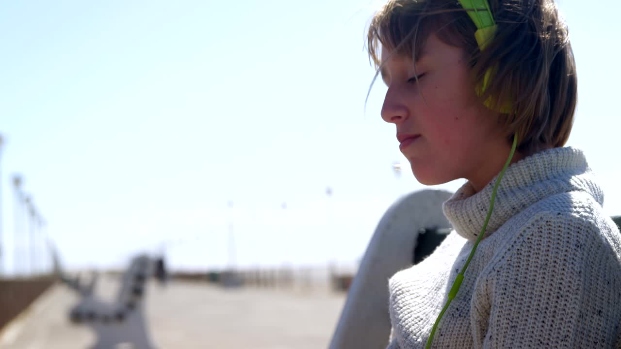 해변 4k에서 헤드폰으로 음악을 듣는 소녀