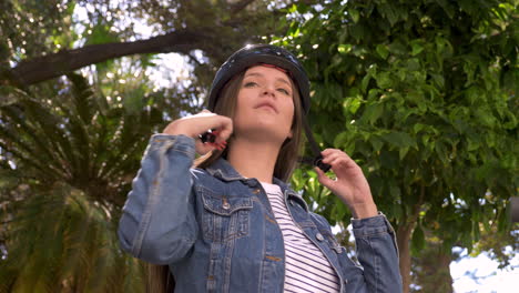 young woman with electric scooter in the city putting on helmet 1