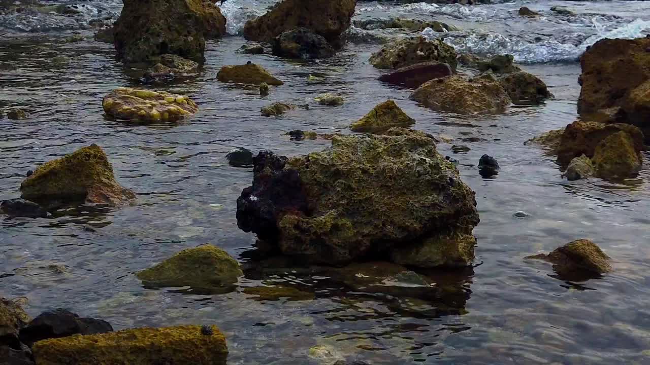 Stille vand, der omdannes til bølgekraft, som slår mod klipperne på kysten.