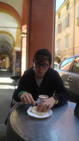 man having coffee and eating bread in a european outdoor cafe